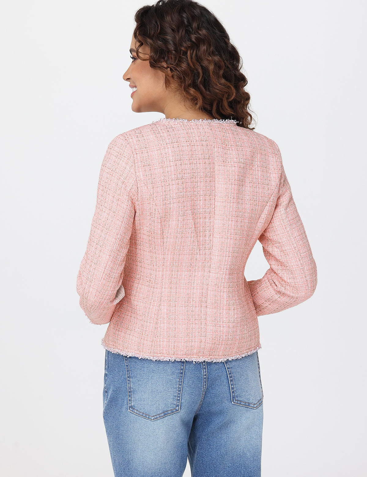 Woman wearing a pink textured top and blue jeans on a white background