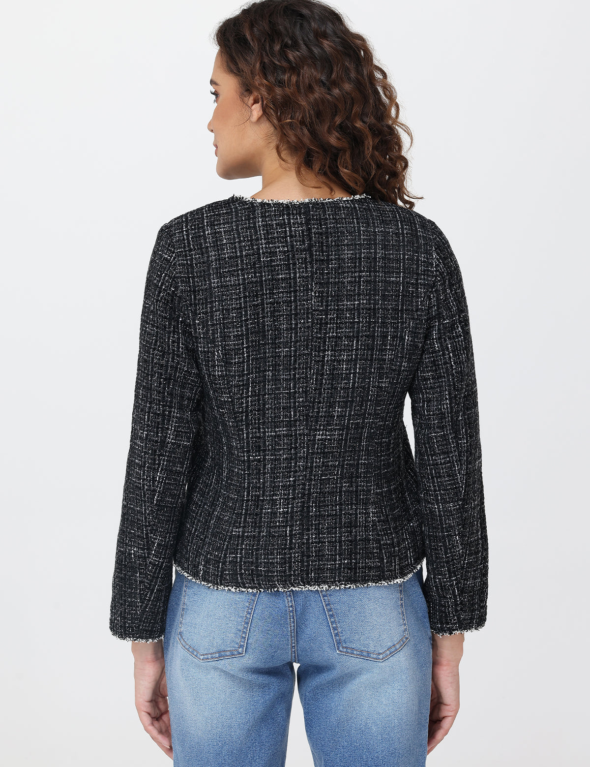 Person wearing a black checkered jacket and blue jeans on a light gray background