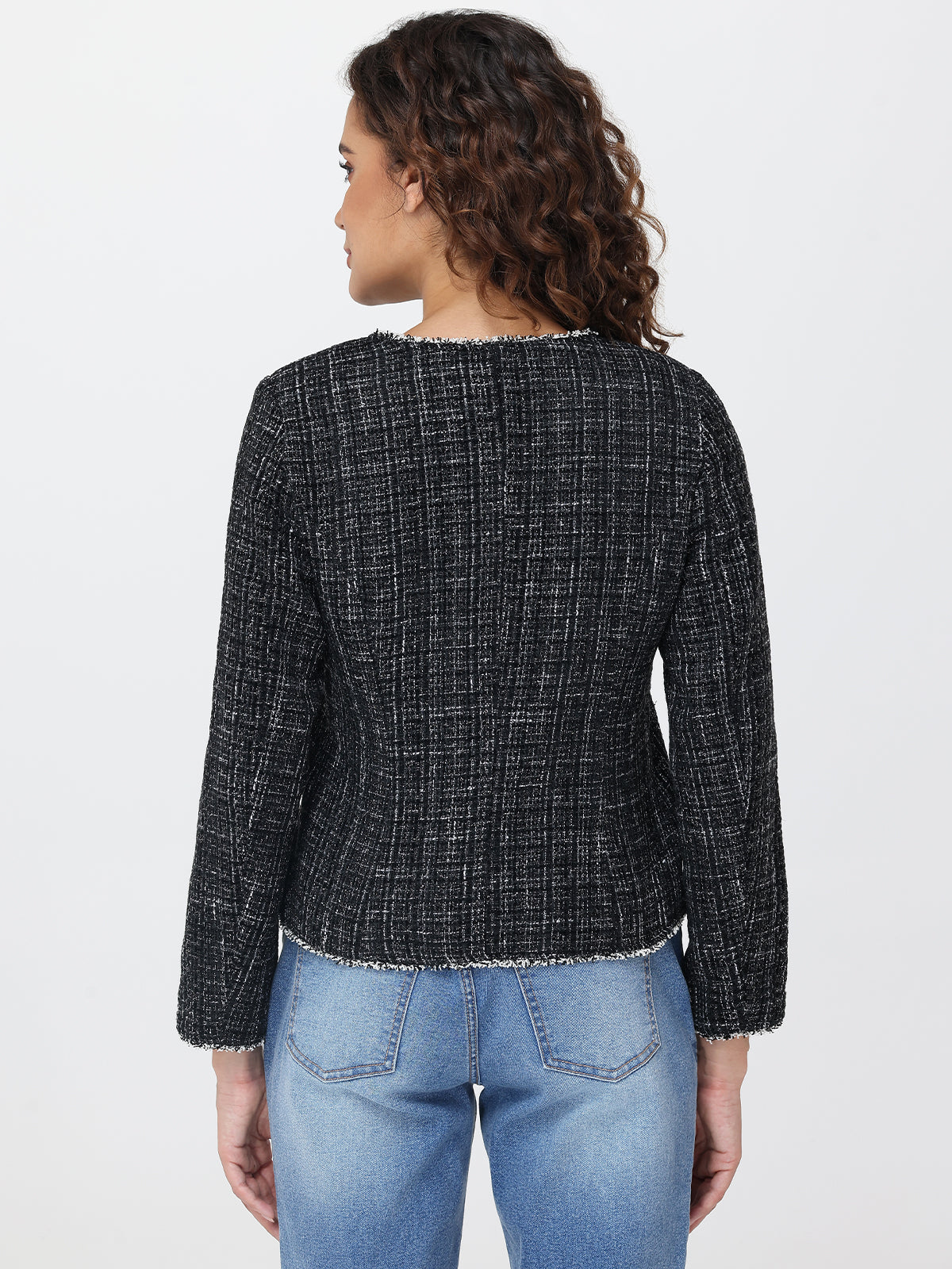 Person wearing a black checkered jacket and blue jeans on a light gray background