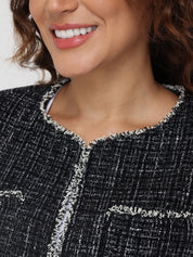 Close-up of a person wearing a black and white textured jacket with a blurred background
