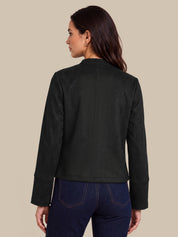A woman shown from the back wearing a black cropped jacket and dark blue jeans, photographed against a solid beige studio background.
