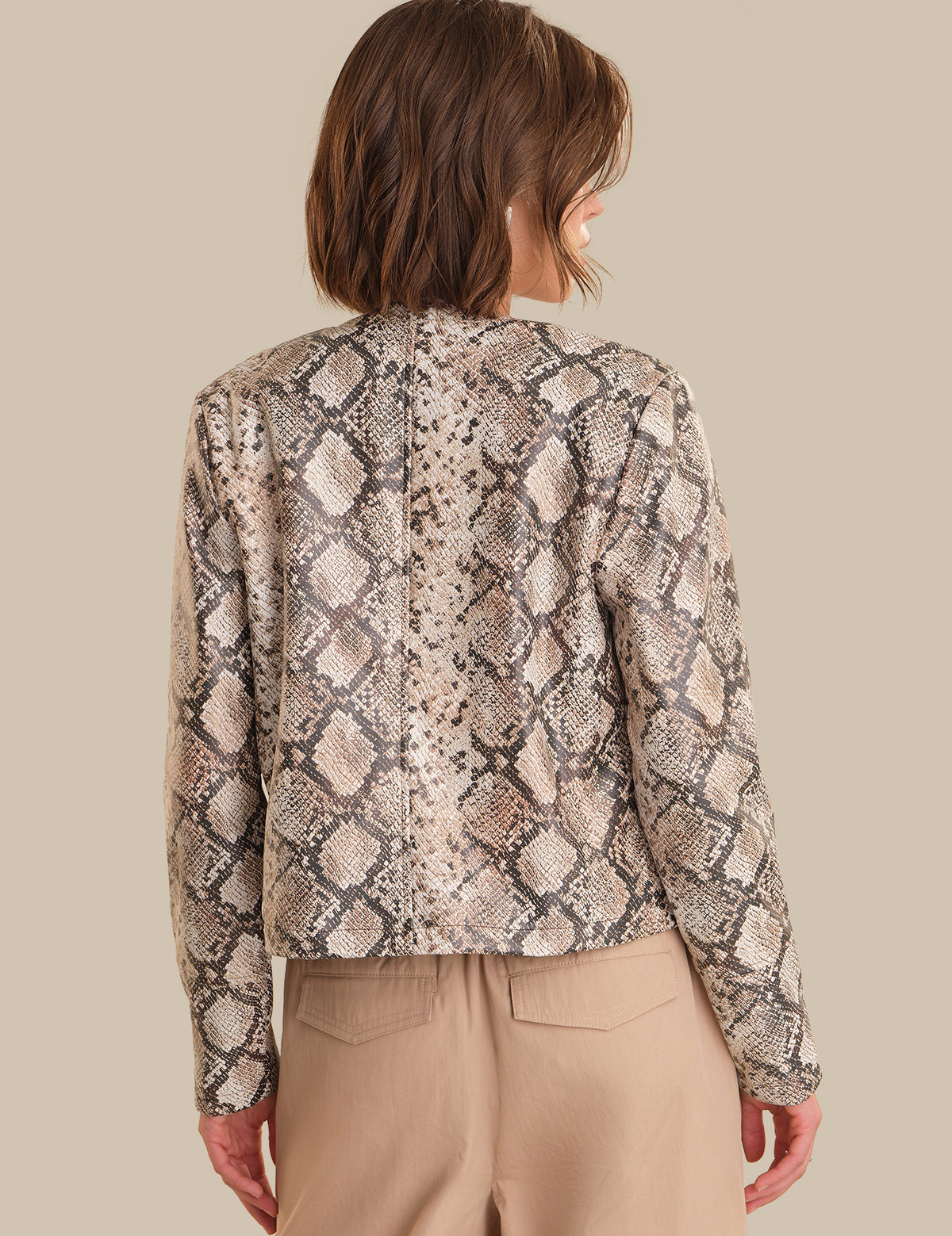 Person wearing a snake print jacket on a beige background