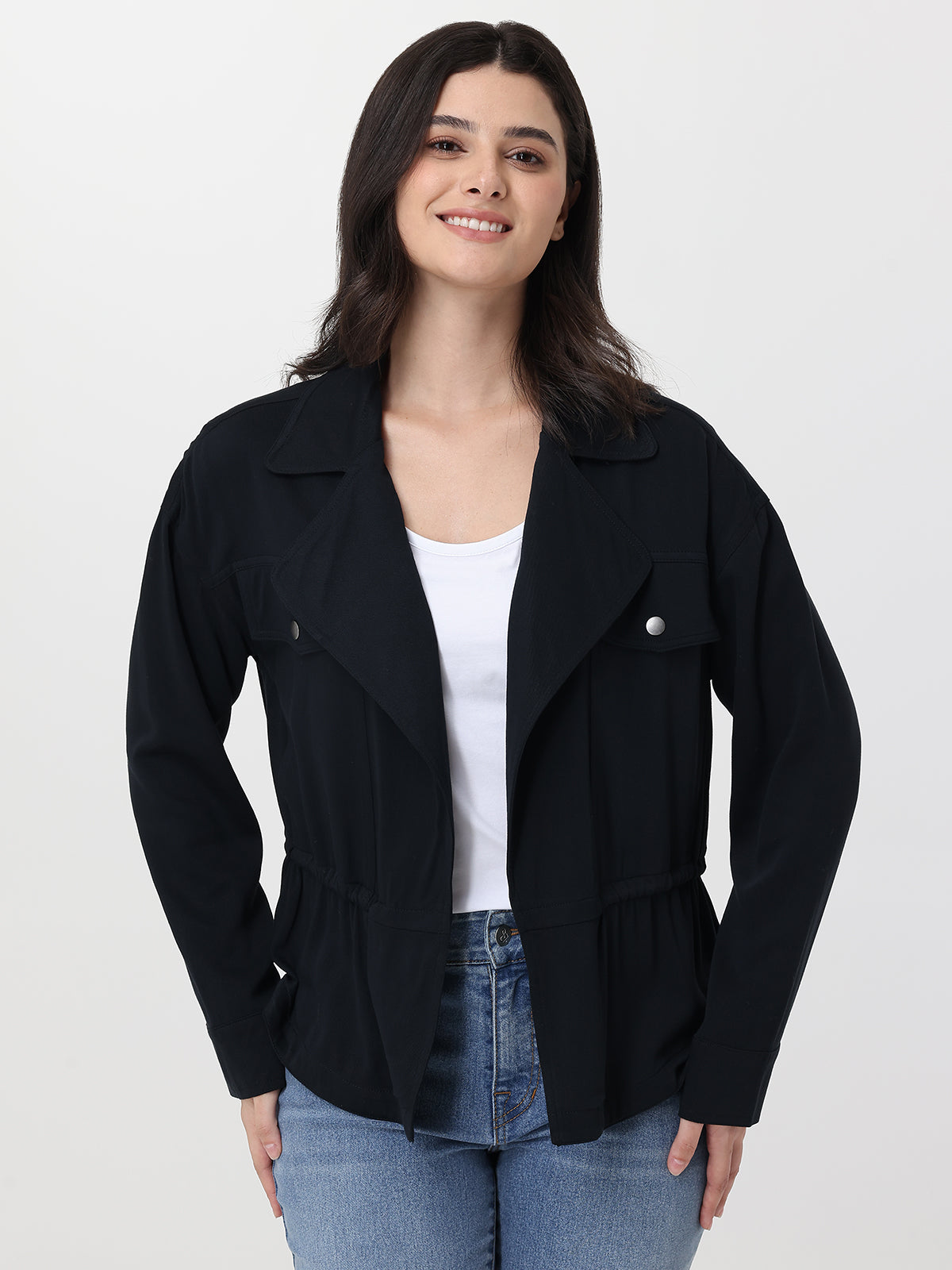 Woman wearing a black jacket over a white shirt and blue jeans on a white background