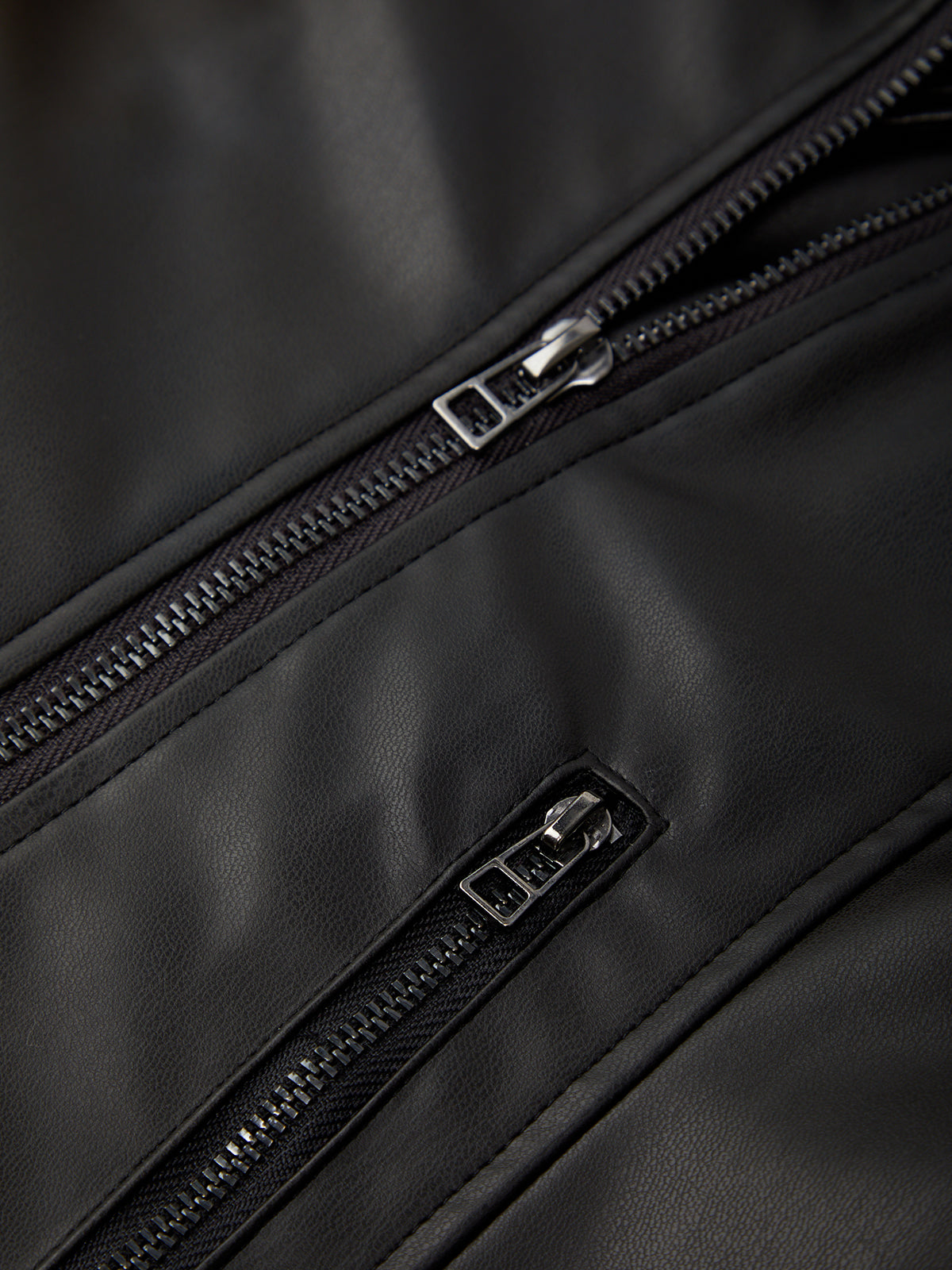 Close-up of a black leather bag with zippers on a dark background