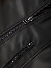 Close-up of a black leather bag with zippers on a dark background