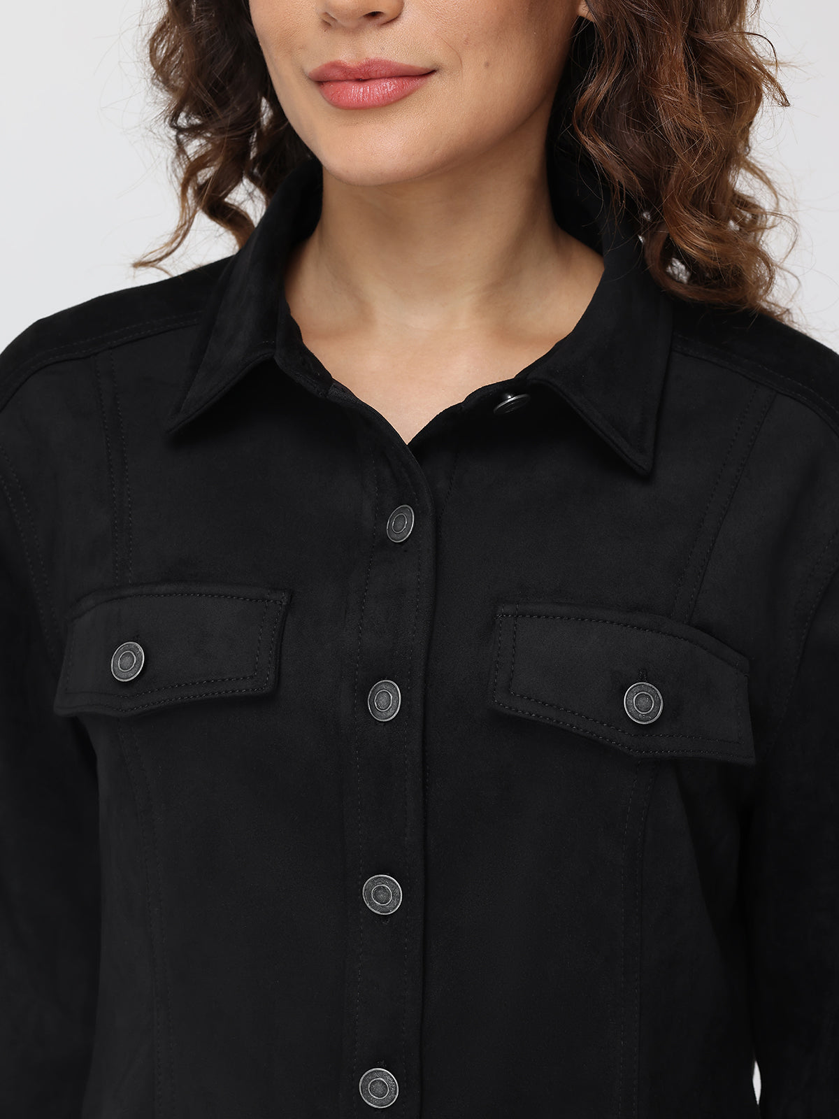 Close-up of a person wearing a black jacket with button details on a plain background