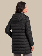 A woman shown from the back wearing a black hooded puffer jacket against a solid beige studio background.