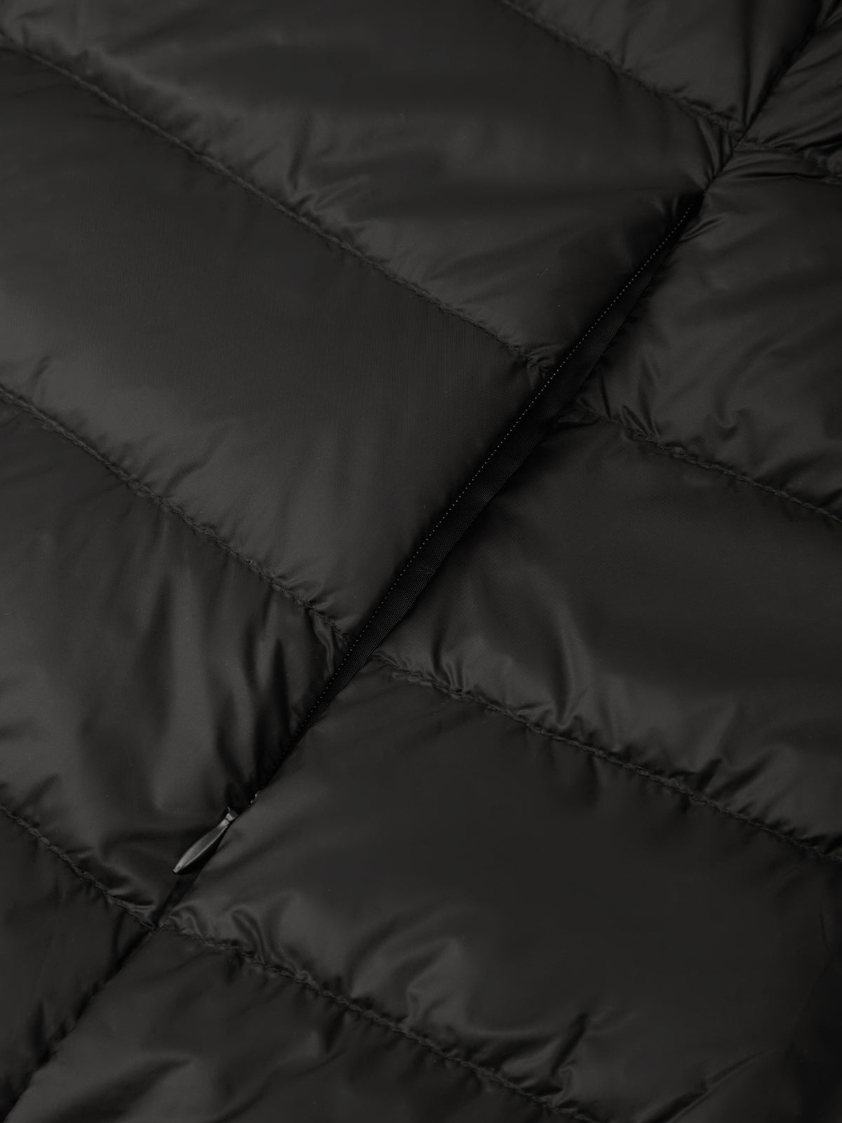 Close-up of a black quilted puffer jacket showing the padded stitching and smooth fabric texture.
