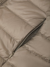 Close-up of a quilted puffer jacket in a warm taupe-beige color, showing the padded stitching and a dark gray zipper.