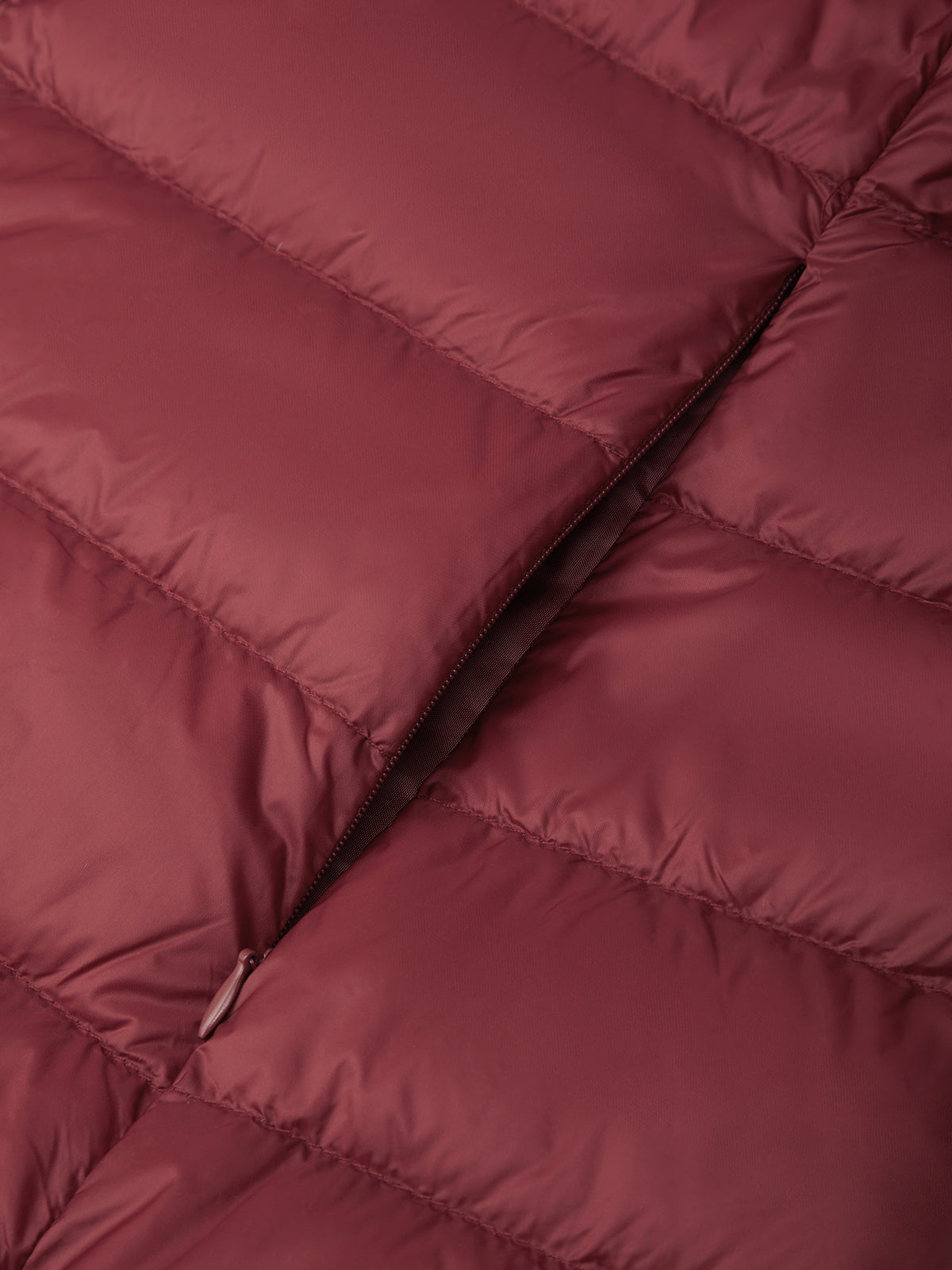 Close-up of a quilted puffer jacket in a dusty rose or mauve color, showing the padded stitching and a zipper detail.