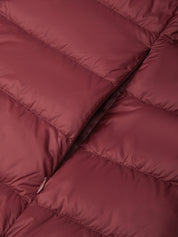 Close-up of a quilted puffer jacket in a dusty rose or mauve color, showing the padded stitching and a zipper detail.