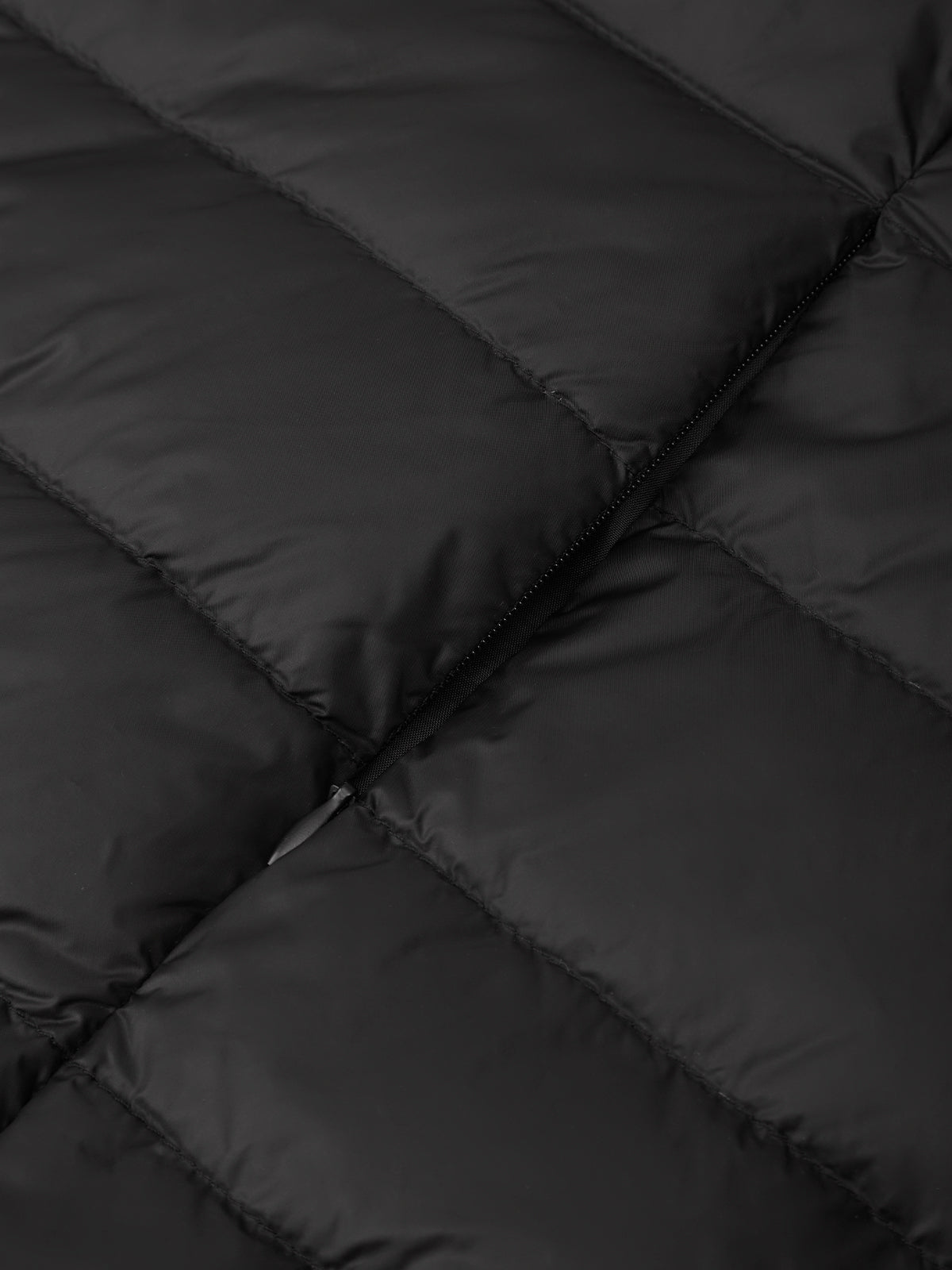 Close-up of a black quilted puffer jacket showing the padded sections and a zipper detail.