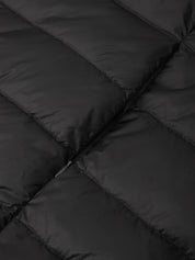 Close-up of a black quilted puffer jacket showing the padded sections and a zipper detail.