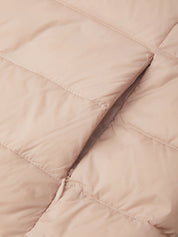 Close-up of a quilted puffer jacket in a light blush pink color, showing the texture of the fabric and a silver zipper detail.