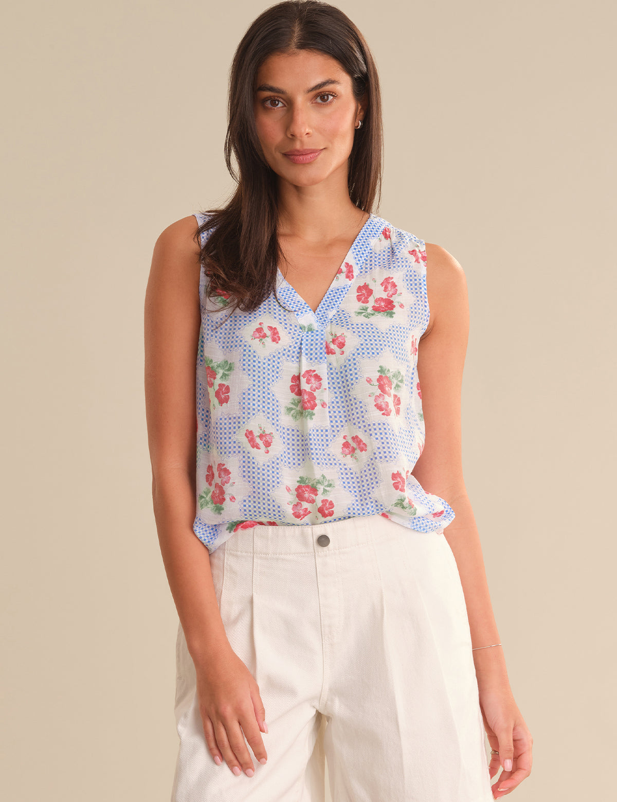 Woman wearing a sleeveless floral blouse with a beige background