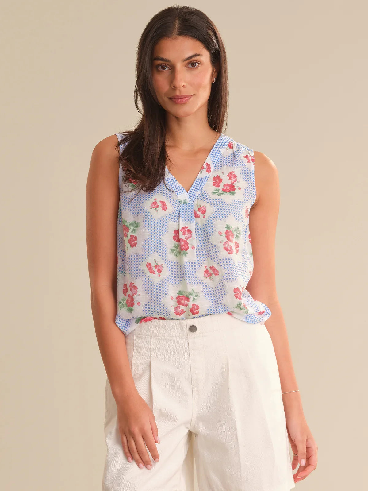Woman wearing a sleeveless floral blouse with a beige background