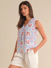 Woman wearing a sleeveless floral top and white shorts on a beige background