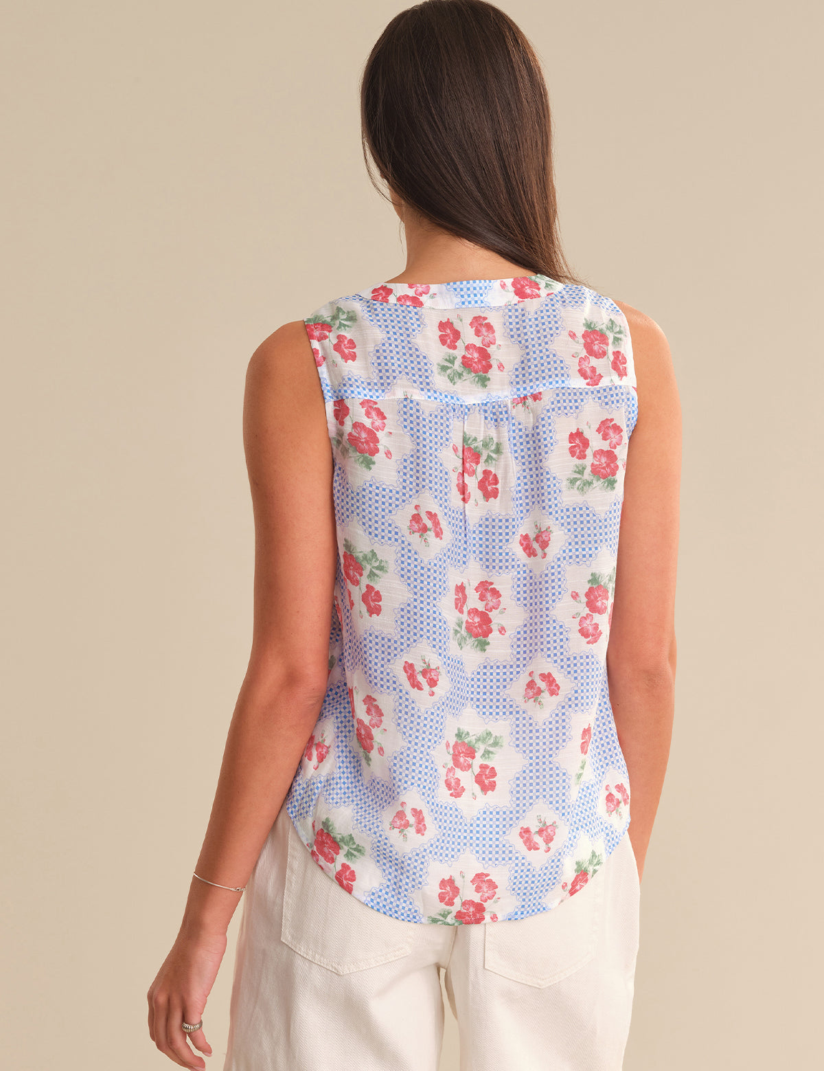 Woman wearing a sleeveless floral top with a beige background