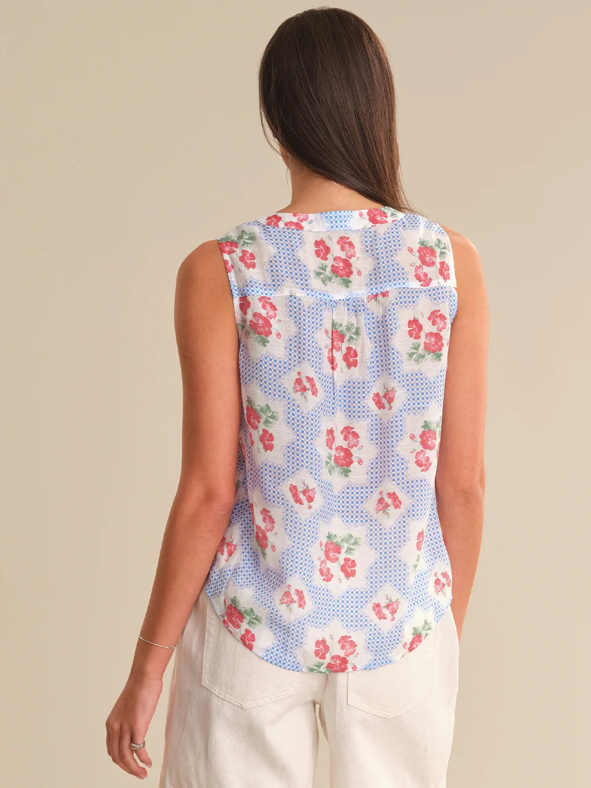 Woman wearing a sleeveless floral top with a beige background