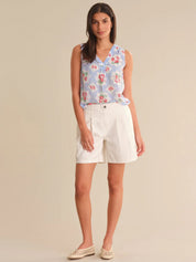 Woman wearing a floral sleeveless top and white shorts on a beige background