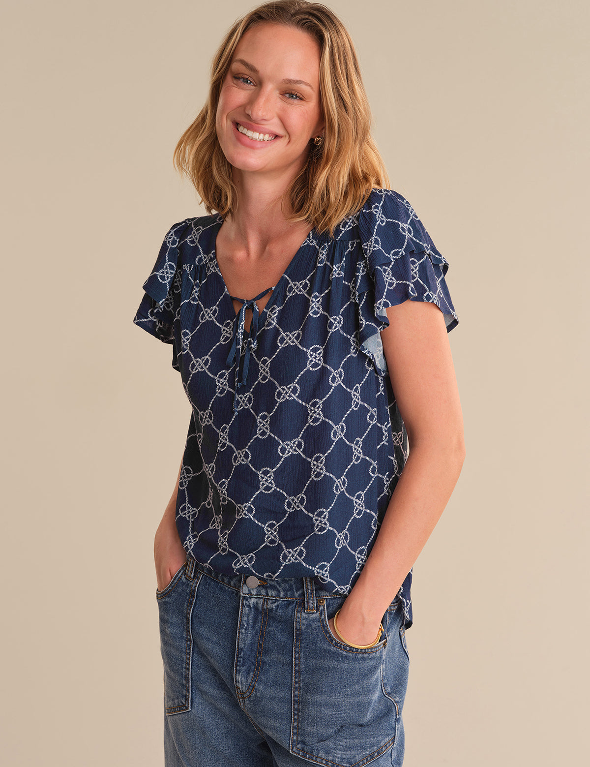 Woman wearing a blue patterned top and jeans on a beige background