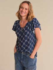 Woman wearing a blue patterned top and jeans on a beige background