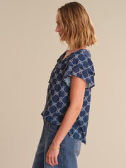 Woman wearing a blue patterned shirt and jeans on a beige background