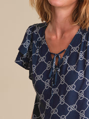 Navy blue blouse with white knot pattern on a beige background