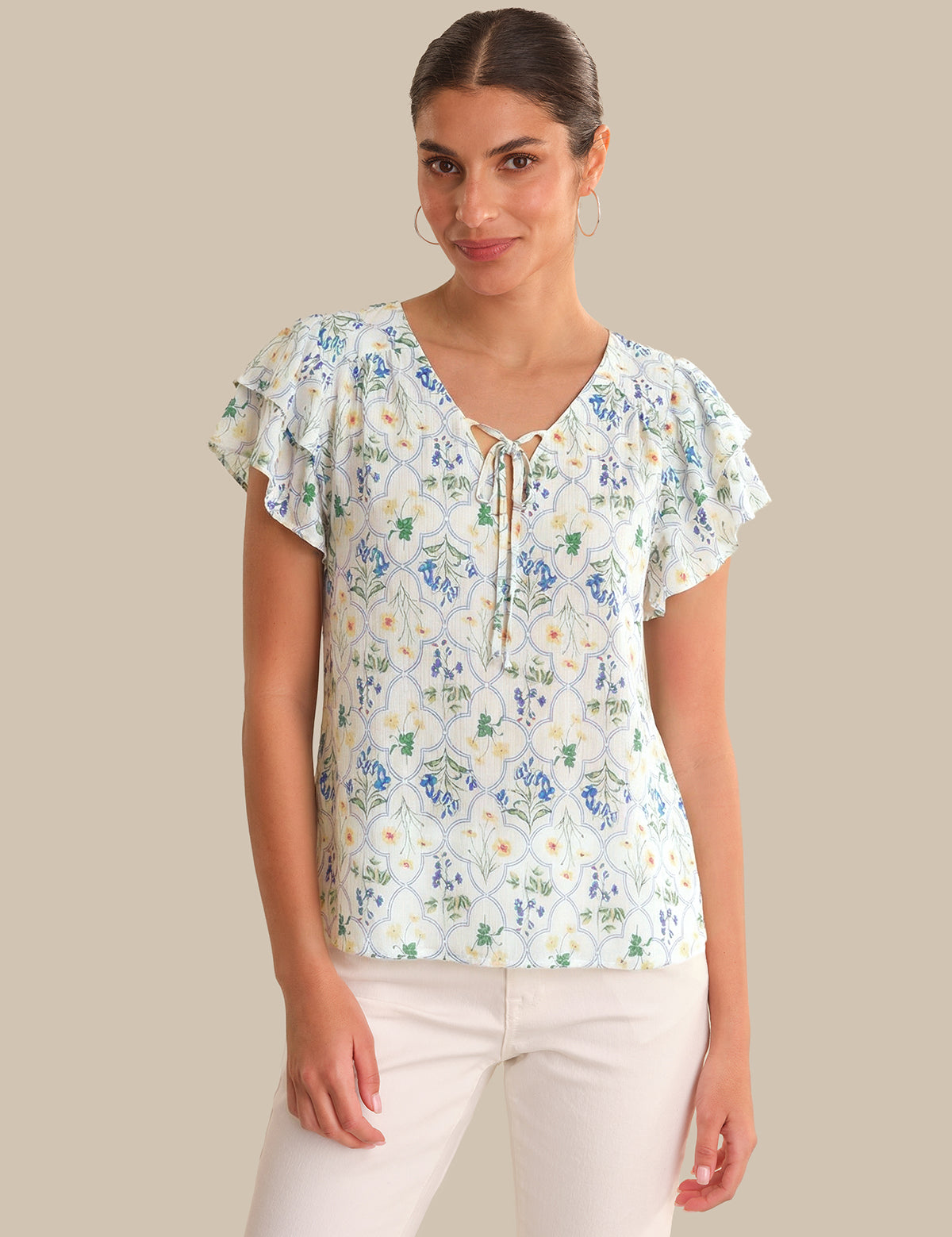 Woman wearing a floral blouse with ruffled sleeves on a beige background