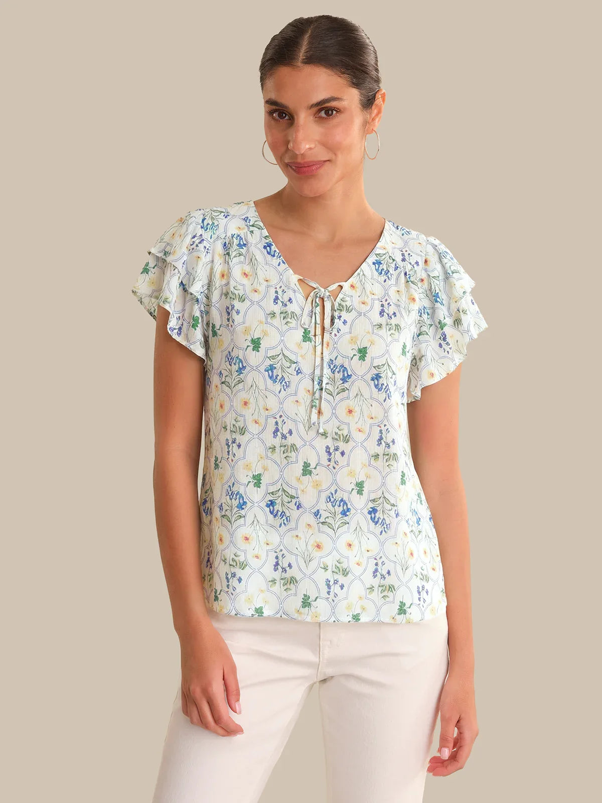 Woman wearing a floral blouse with ruffled sleeves on a beige background