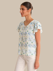 Woman wearing a floral blouse with ruffled sleeves on a beige background