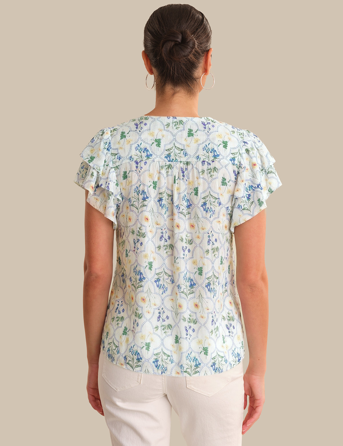 Woman wearing a floral blouse with ruffled sleeves on a beige background