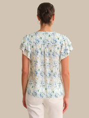 Woman wearing a floral blouse with ruffled sleeves on a beige background