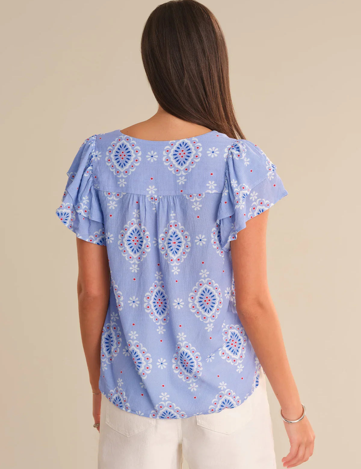 Woman wearing a blue patterned blouse against a beige background