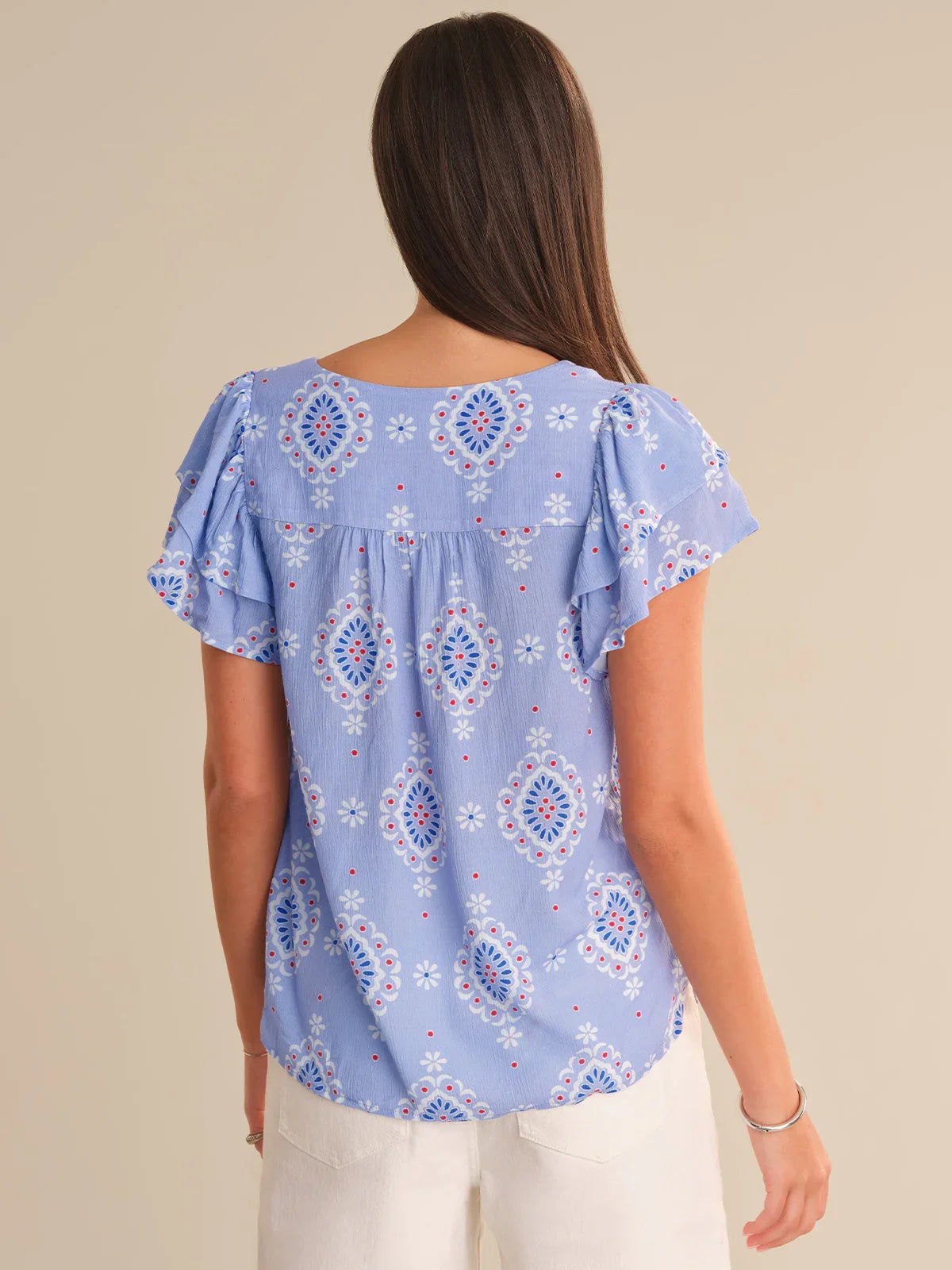 Woman wearing a blue patterned blouse against a beige background