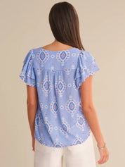 Woman wearing a blue patterned blouse against a beige background