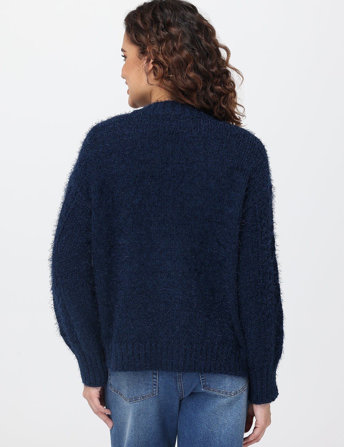 Person wearing a dark blue cardigan and jeans on a white background