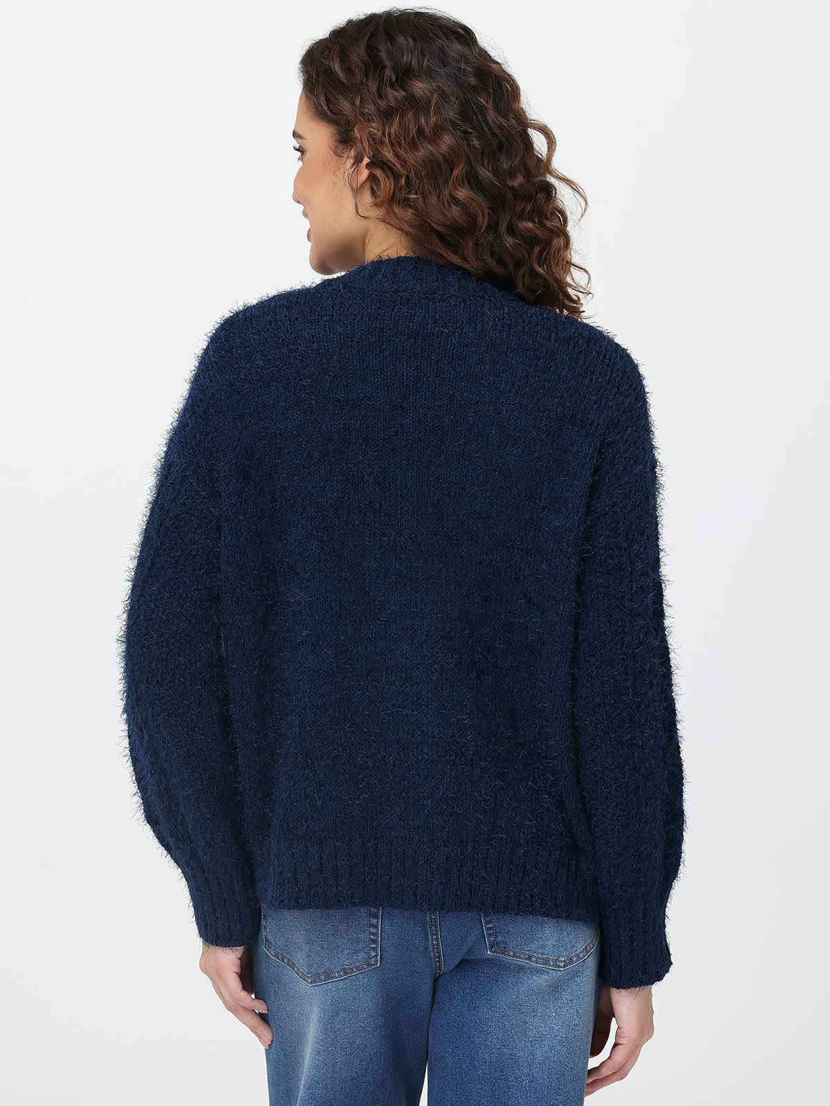 Person wearing a dark blue cardigan and jeans on a white background