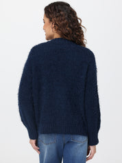 Person wearing a dark blue cardigan and jeans on a white background
