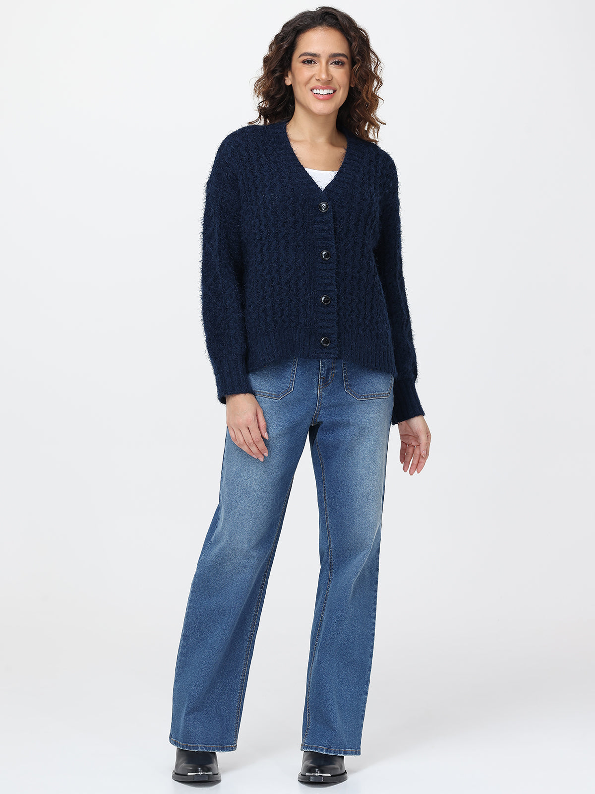 Woman wearing a navy cardigan and blue jeans on a white background