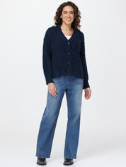 Woman wearing a navy cardigan and blue jeans on a white background