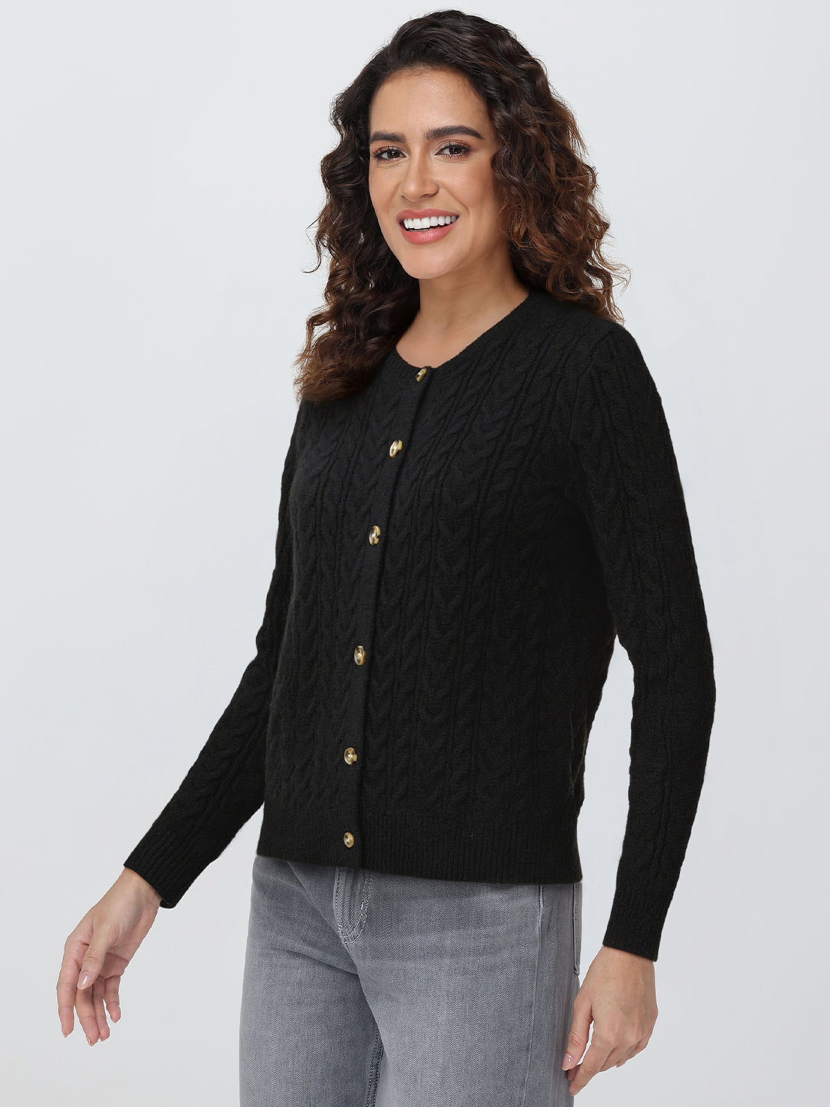 Woman wearing a black cardigan with gold buttons on a white background