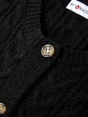 Close-up of a black cardigan with buttons and a brand label.