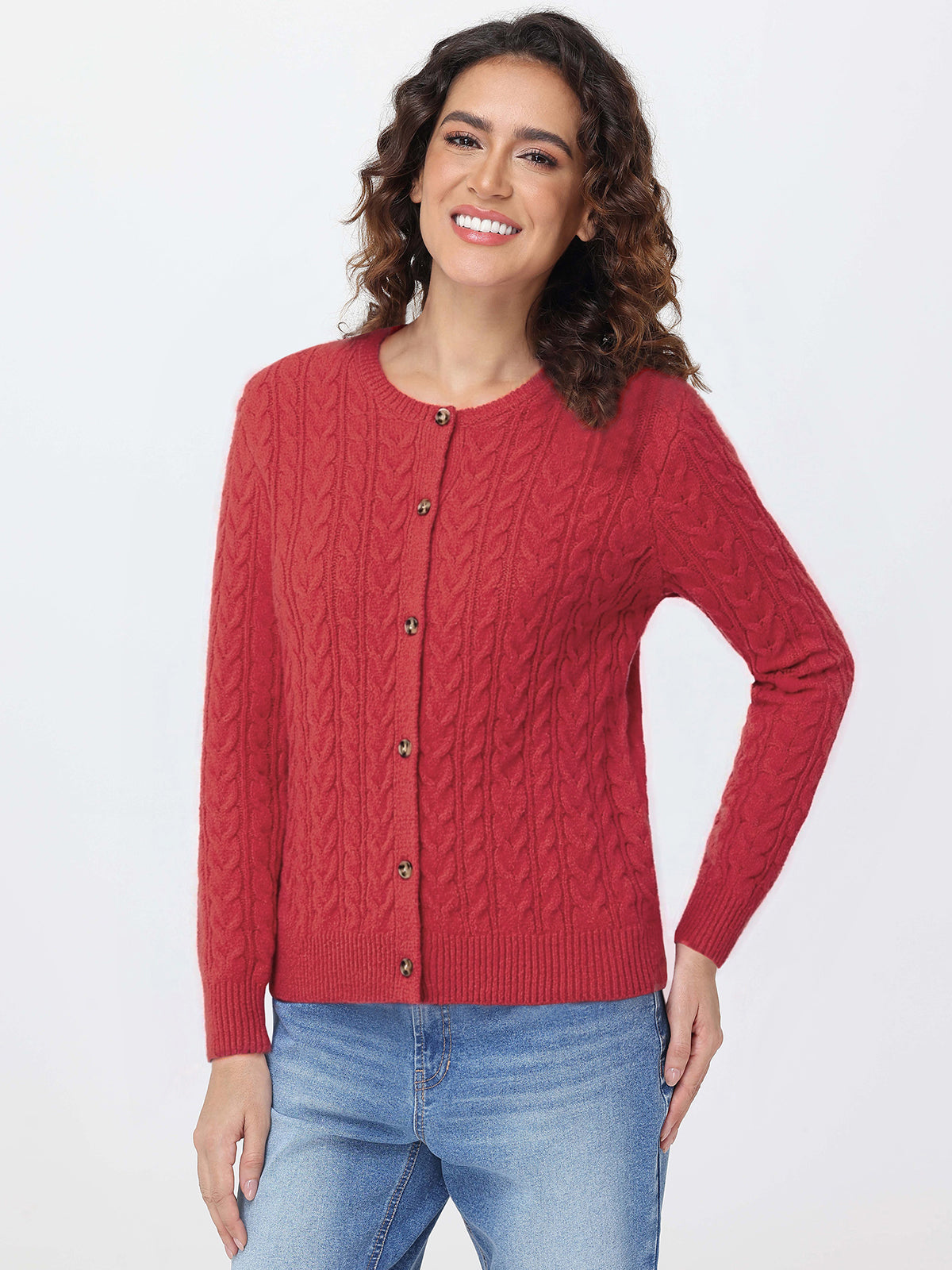 Woman wearing a red cable knit cardigan and blue jeans on a white background