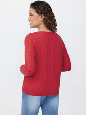 Woman wearing a red cable knit sweater and blue jeans on a white background