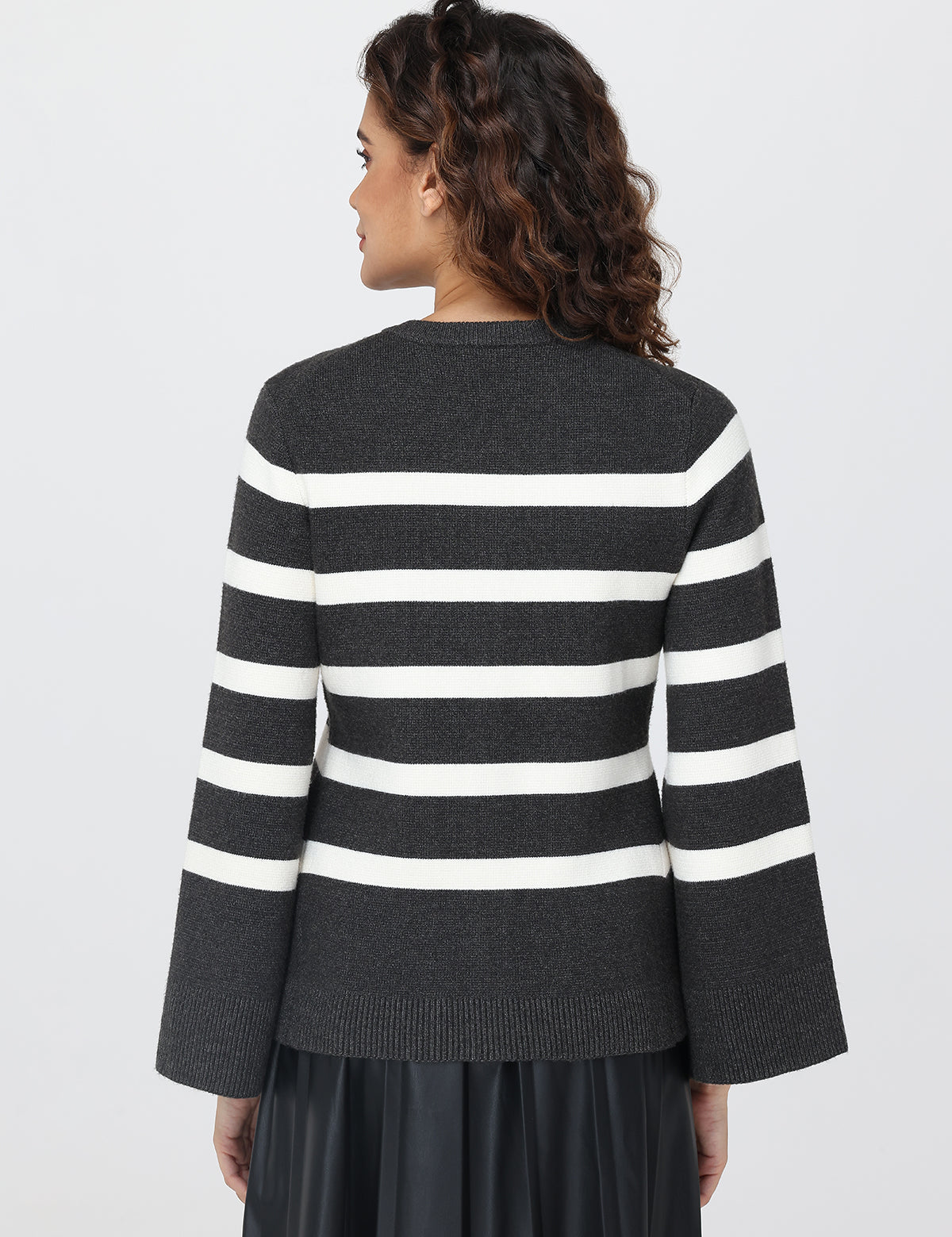Woman wearing a black and white striped  cardigan on a light gray background