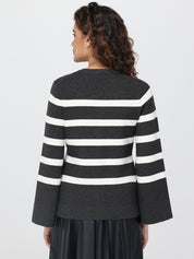 Woman wearing a black and white striped  cardigan on a light gray background