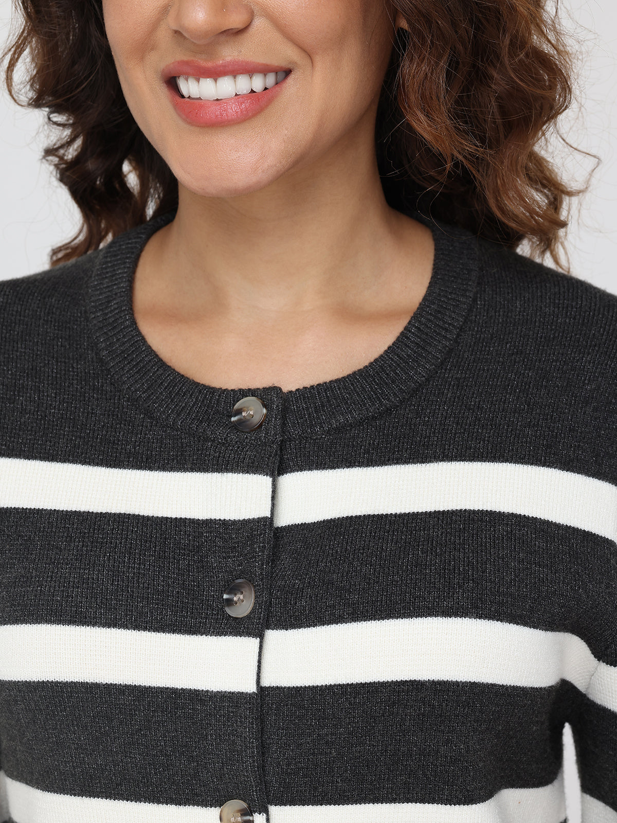 Close-up of a person wearing a black and white striped cardigan with a neutral background