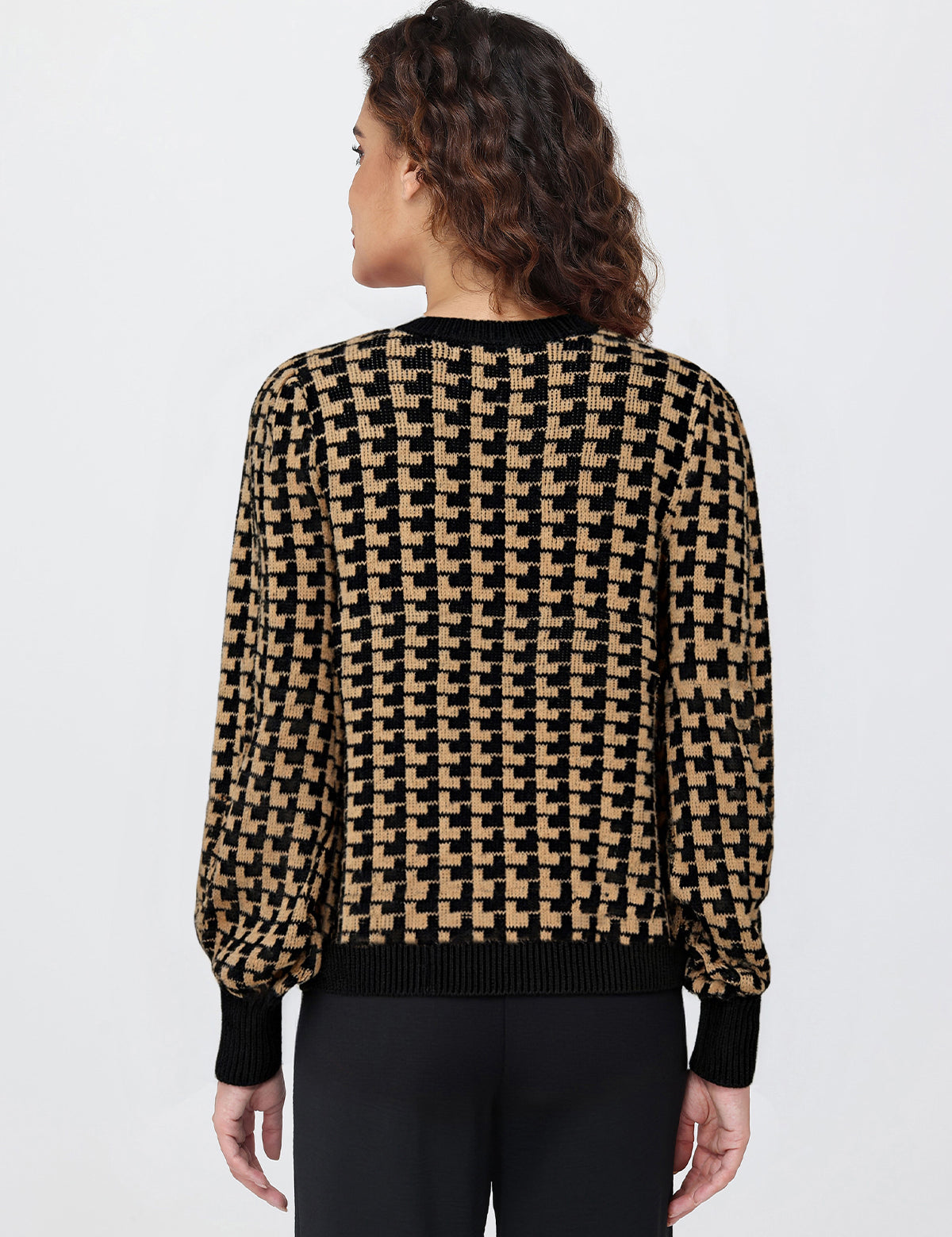 Person wearing a houndstooth patterned sweater on a plain background