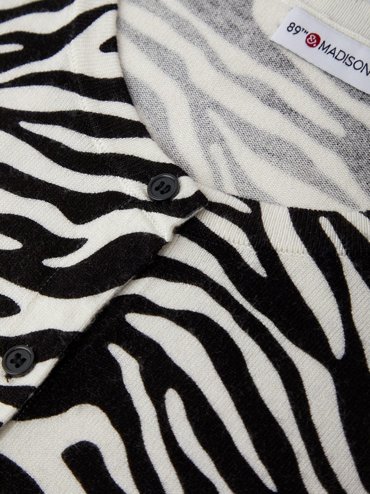 Close-up of zebra-patterned fabric with a button and visible brand label.